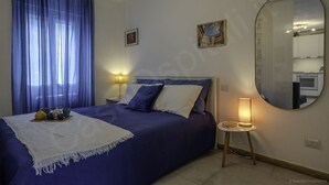 Une chambre à coucher avec un lit, des lampes de chevet, un miroir et une fenêtre avec des rideaux.