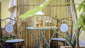Un espace patio aménagé avec deux chaises en métal, une petite table et une bouteille de Corona Extra.