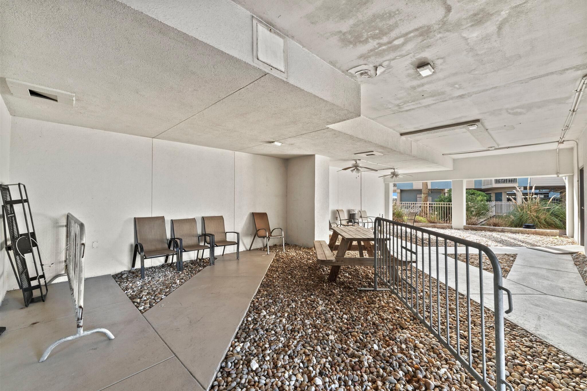 A modern indoor space with a concrete ceiling, a table with chairs, and a seating area with benches.
