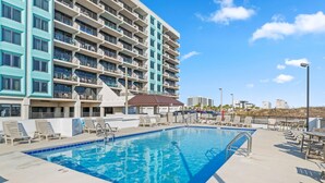 A hotel with a swimming pool, multiple balconies, and a clear blue sky. - Island Winds West Unit 575 (Gulf Shores)