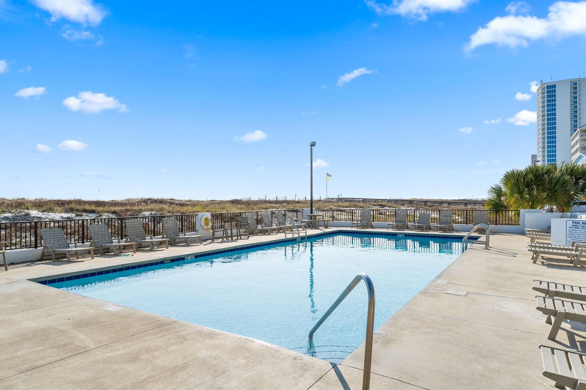 A swimming pool with lounge chairs and a flagpole.