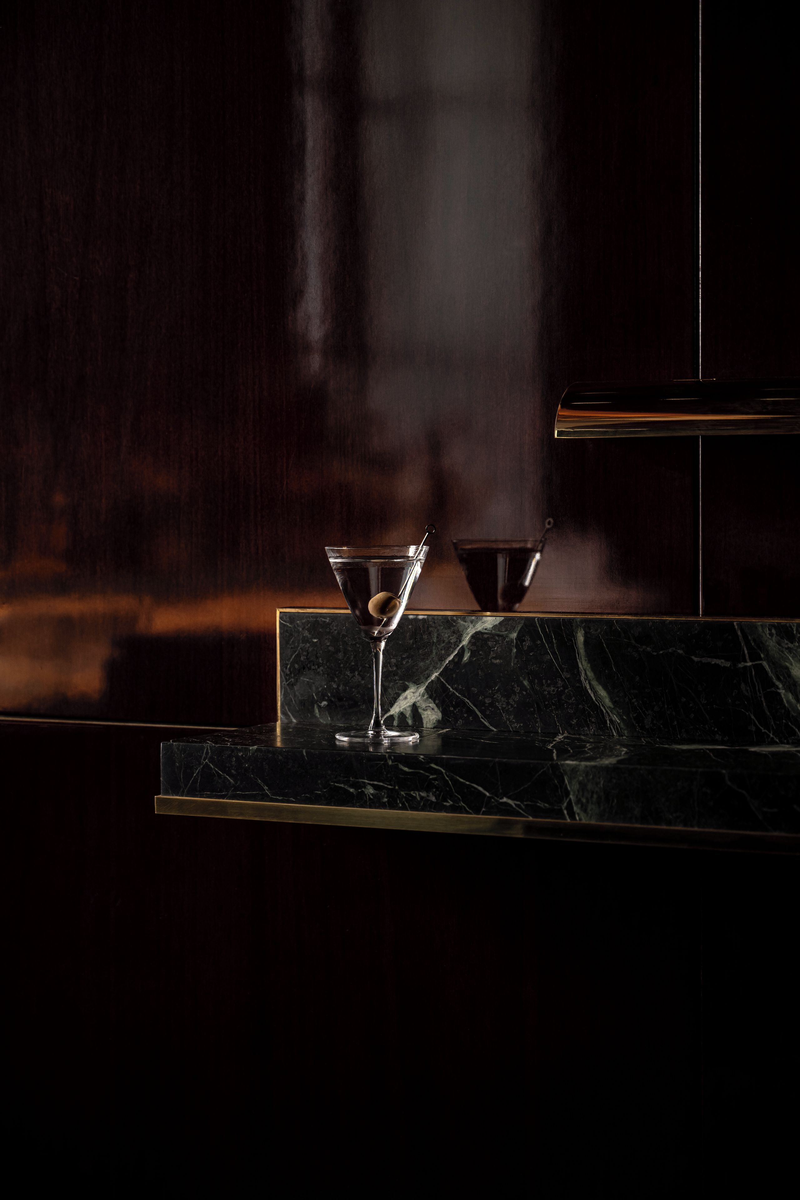 A bar area with a marble countertop, a glass with a stemmed glass, and a steam vent.