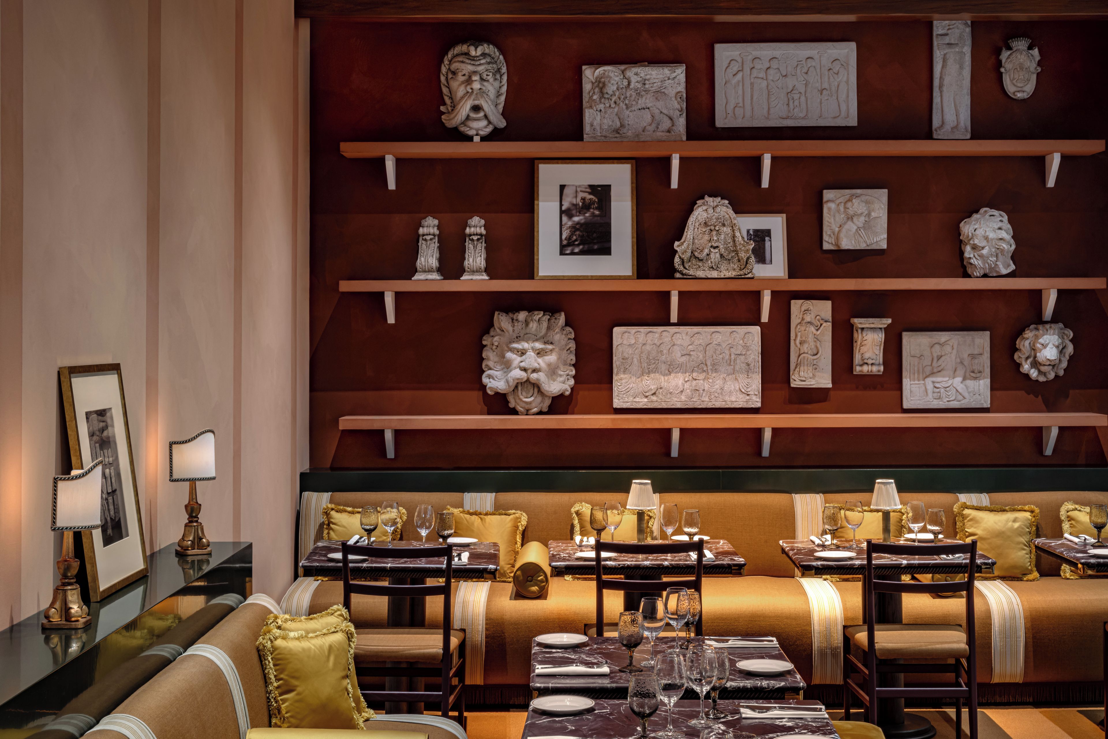 Un ristorante con un'ampia sala da pranzo, numerosi tavoli e una parete di opere d'arte e sculture.