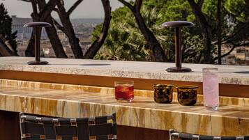 Un área de bar con vista a árboles y un paisaje urbano distante.