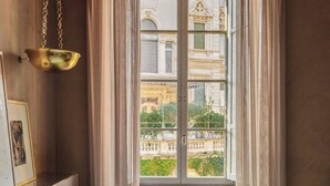 A room with a bed, a hanging light fixture, and a window with curtains. - Experimental Roma (Rome)
