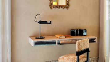 A hotel room with a desk, chair, and a mirror on the wall.