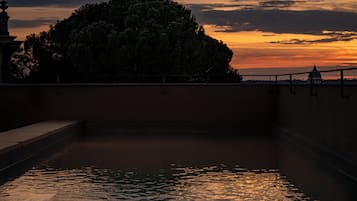 Una piscina rectangular con una vista despejada del cielo y un edificio distante.