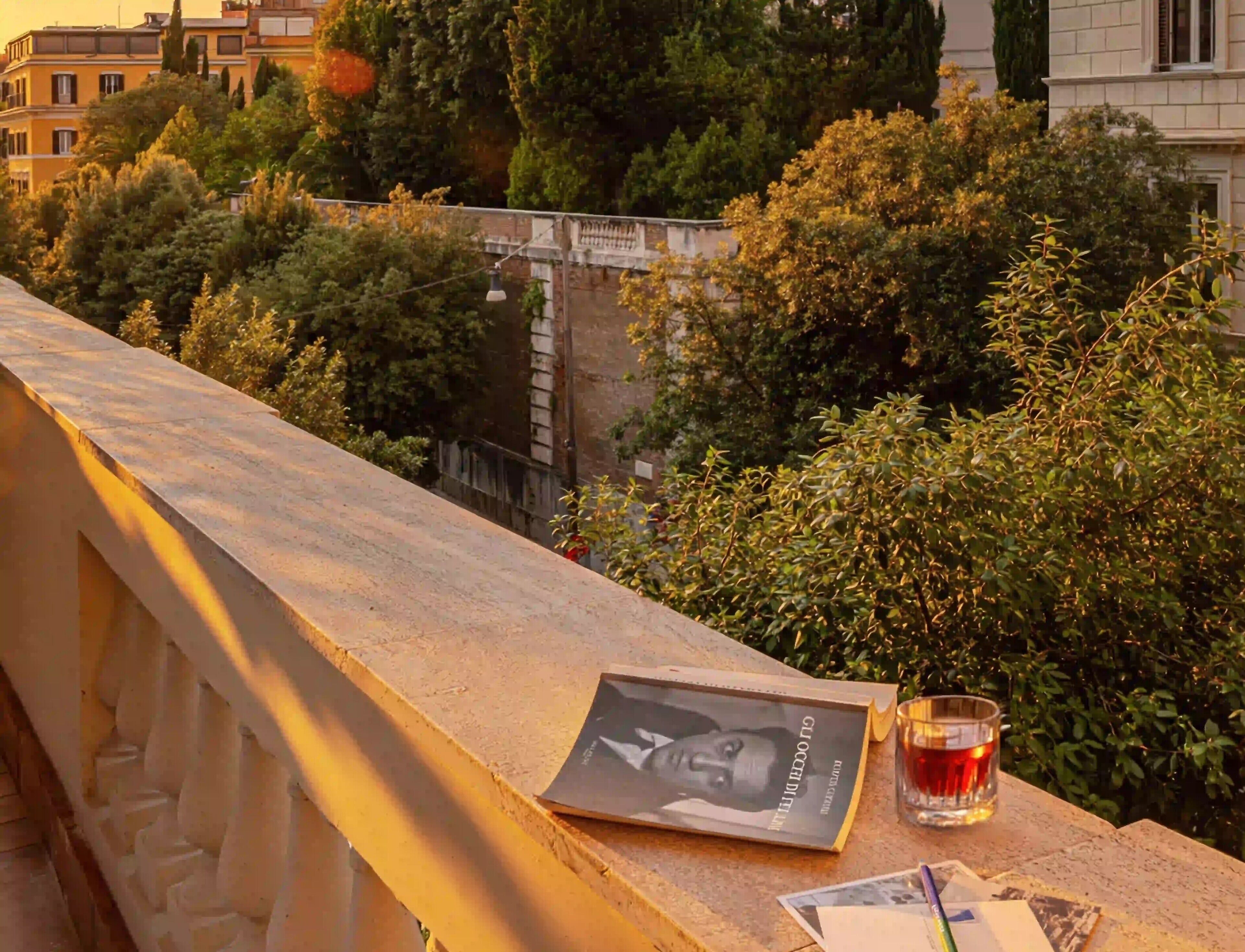 A balcony with a glass of drink, a book, and a postcard.