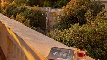 A balcony with a glass of drink, a book, and a postcard.