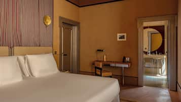 A hotel room with a bed, a desk, a chair, a mirror, and a door.