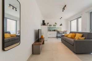 Ein modernes Wohnzimmer mit einer Couch, einem Fernseher, einem Couchtisch und einem großen Spiegel.