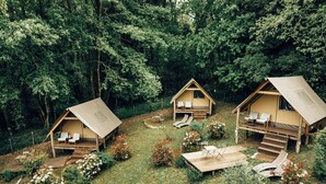 Three wooden cabins with outdoor seating and a small garden area. - GLAMPING PIAN DELLE GINESTRE (Sassetta)