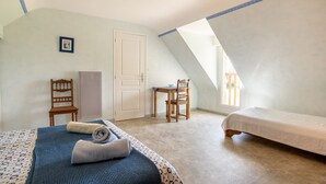 A bedroom with a sloped ceiling, a bed, a chair, a desk, and a door. - Comfortable Cottage Between Land and Sea with Wi-Fi in Pont-Aven (Pont-Aven)