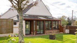 A house with a covered porch, a lawn, and a tree. - Comfortable Cottage Between Land and Sea with Wi-Fi in Pont-Aven (Pont-Aven)