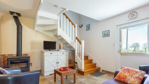 A living room with a fireplace, a staircase, a sofa, and a television. - Comfortable Cottage Between Land and Sea with Wi-Fi in Pont-Aven (Pont-Aven)