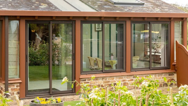 A conservatory with sliding glass doors, a stone foundation, and a garden with a barrel planter. - Comfortable Cottage Between Land and Sea with Wi-Fi in Pont-Aven (Pont-Aven)