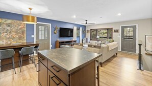 A modern kitchen with a bar area, a dining table, and a seating area with a sofa and chairs. - Deadwood Pines Hideaway (Sturgis)