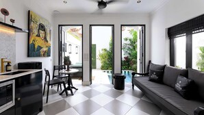 Una cucina moderna con zona pranzo, divano e vista su piscina e vegetazione.