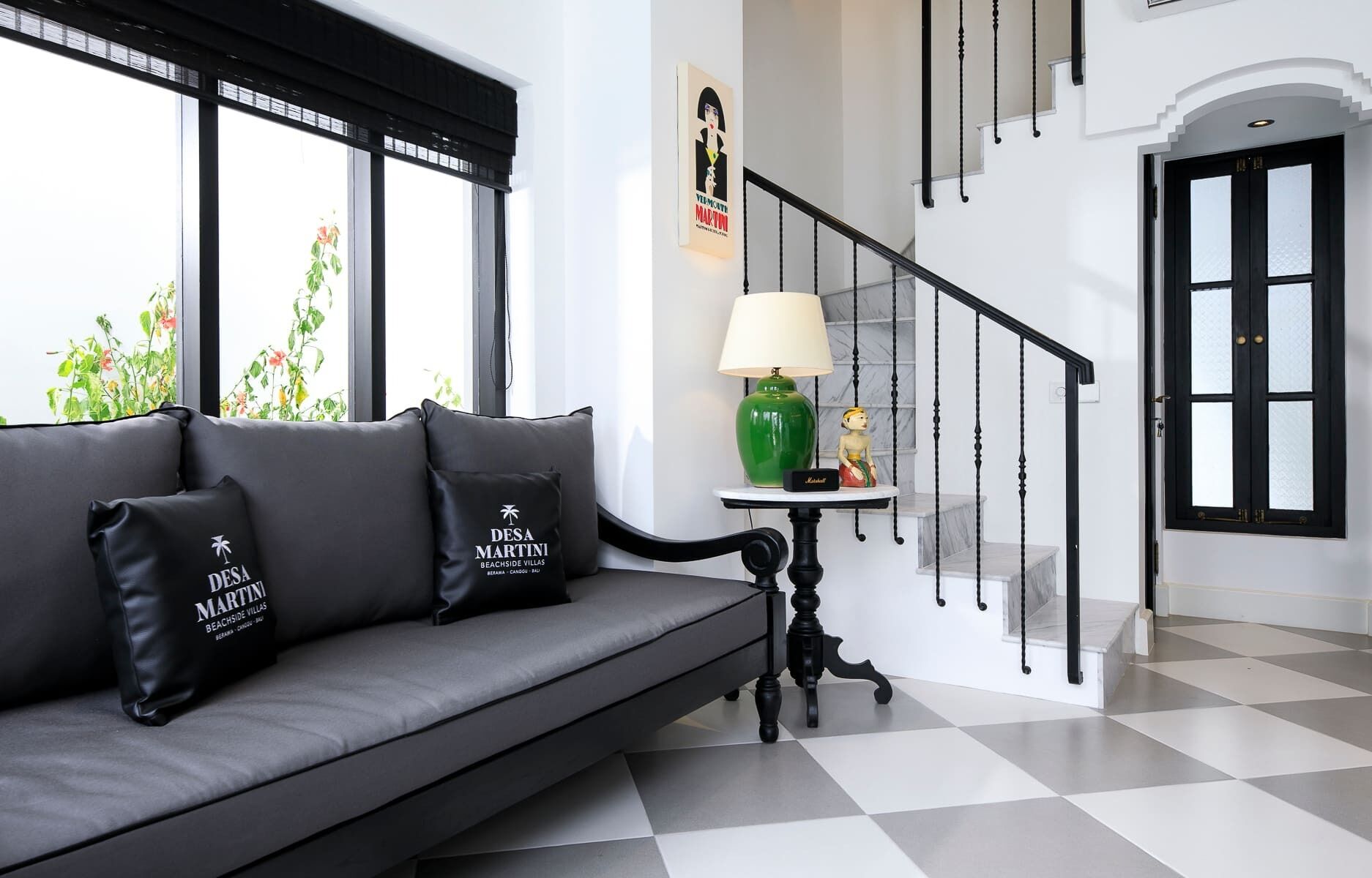 A modern interior with a grey sofa, a green lamp, and a staircase with black railings.