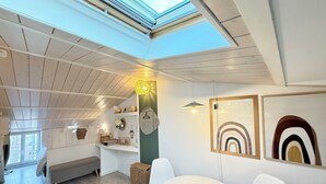 Ein modernes Interieur mit Oberlichter, weißen Wänden, Holzboden und einem runden Tisch mit Stühlen.