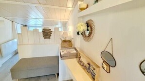 Ein modernes, minimalistisches Zimmer mit Holzboden, einer eingebauten Sitzbank, einem kleinen Tisch mit Spiegel und Wanddekoration.