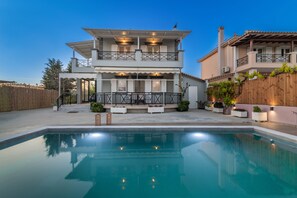 Una casa de dos pisos con una piscina al frente.