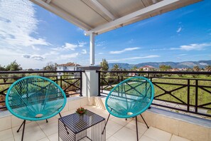 Ein Balkon mit zwei türkisfarbenen Stühlen, einem kleinen Tisch und einem Blumentopf.