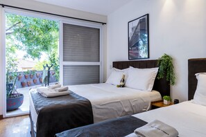 Une chambre d’hôtel avec un lit, une table de chevet, une fenêtre donnant sur un paysage verdoyant et un tableau encadré au mur.