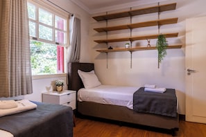 Ein Schlafzimmer mit einem Bett, Nachttischen, einem Kleiderschrank und einem Fenster mit Vorhängen.
