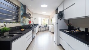 A modern kitchen with a central island, built-in appliances, and a view to the outside. - Casa a 450m Parque Ipiranga (São Paulo)