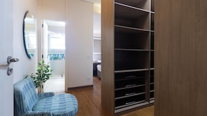 A room with a wooden floor, a striped chair, a large closet with multiple shelves, and a door leading to another room. - Casa a 450m Parque Ipiranga (São Paulo)
