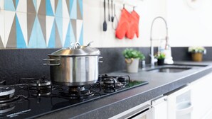A kitchen with a stove, pots, and a backsplash with geometric patterns. - Casa a 450m Parque Ipiranga (São Paulo)