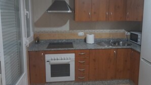 A kitchen with wooden cabinets, a built-in oven, a microwave, and a sink. - Apartment 'Piso Centroolula' with Balcony and Air Conditioning (Olula del Río)