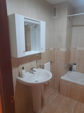 A bathroom with a white sink, a mirror above it, and a white bathtub. - Apartment 'Piso Centroolula' with Balcony and Air Conditioning (Olula del Río)