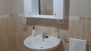 A bathroom with a pedestal sink, a mirror above it, and a towel hanging on a rack. - Apartment 'Piso Centroolula' with Balcony and Air Conditioning (Olula del Río)
