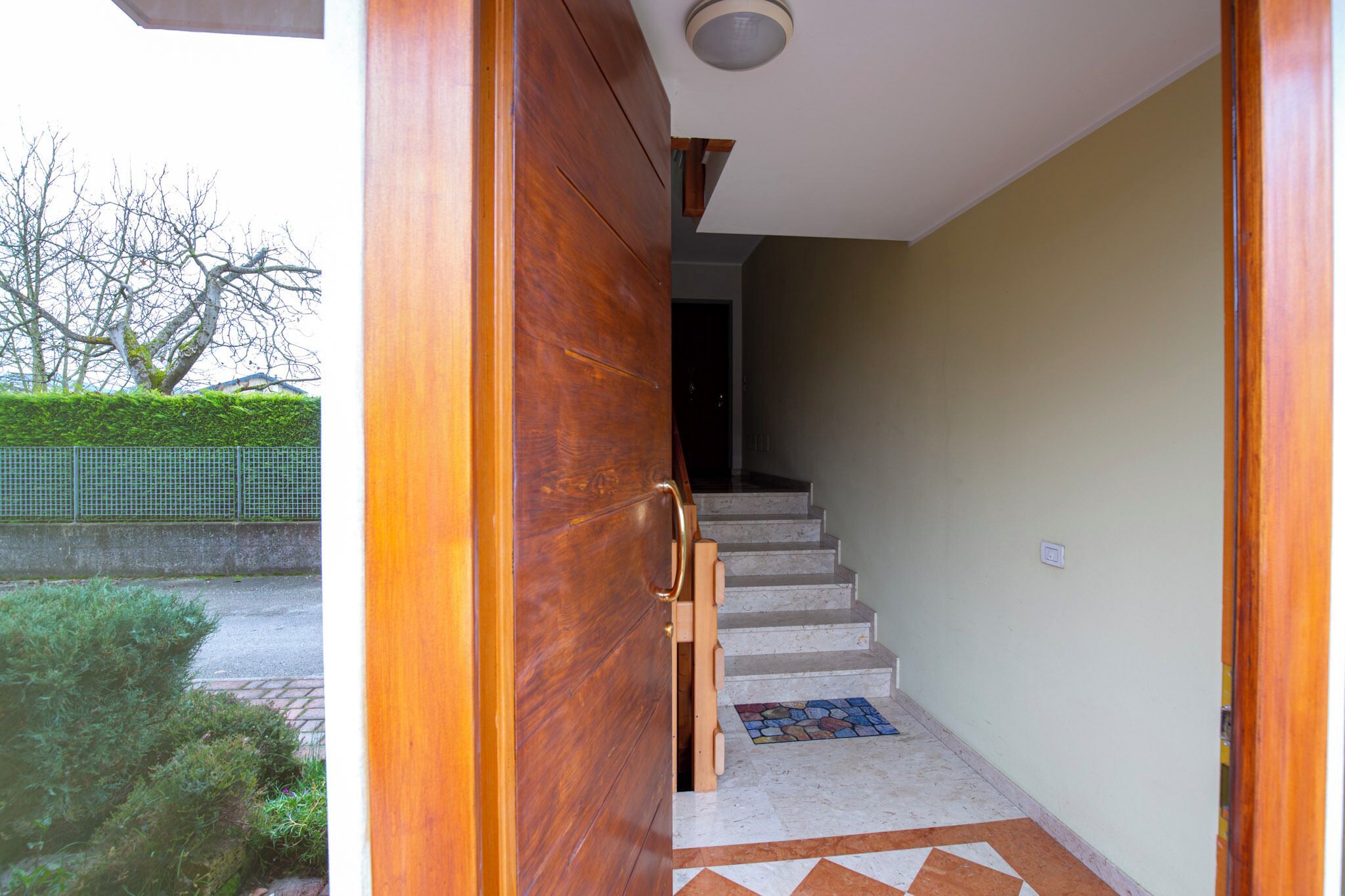 Une porte en bois qui donne sur un escalier dont le sol est recouvert d’un motif décoratif.