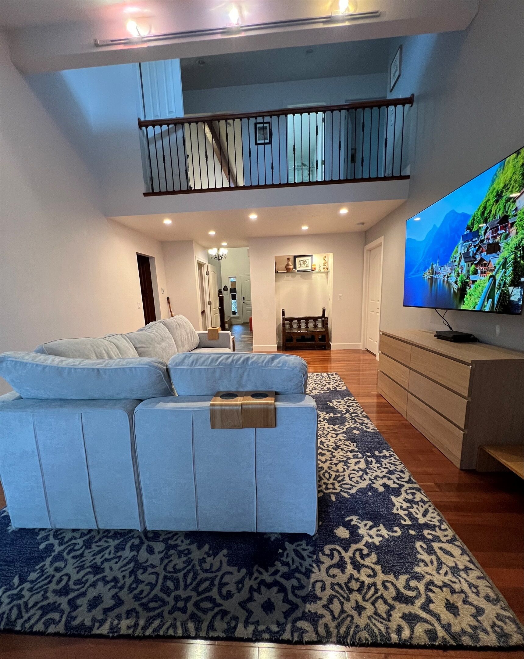 A modern living room with a sectional sofa, a large flat-screen TV, and a patterned rug.