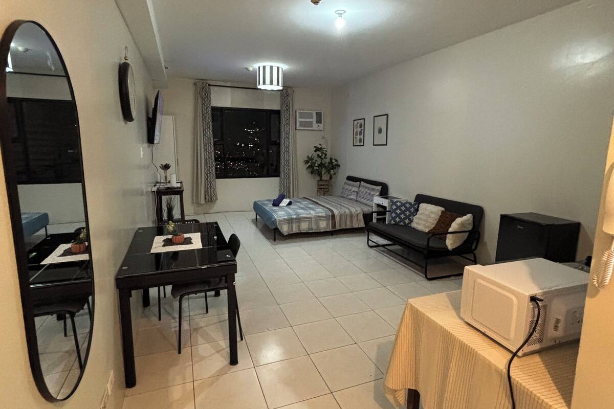 A living room with a dining table, sofa, and a TV stand.