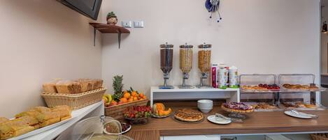 A buffet setup with various food items, including bread, fruits, and dairy products.
