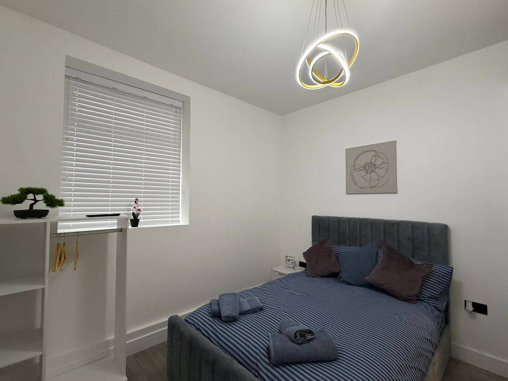 A modern bedroom with a bed, bedside table, and a unique circular light fixture.