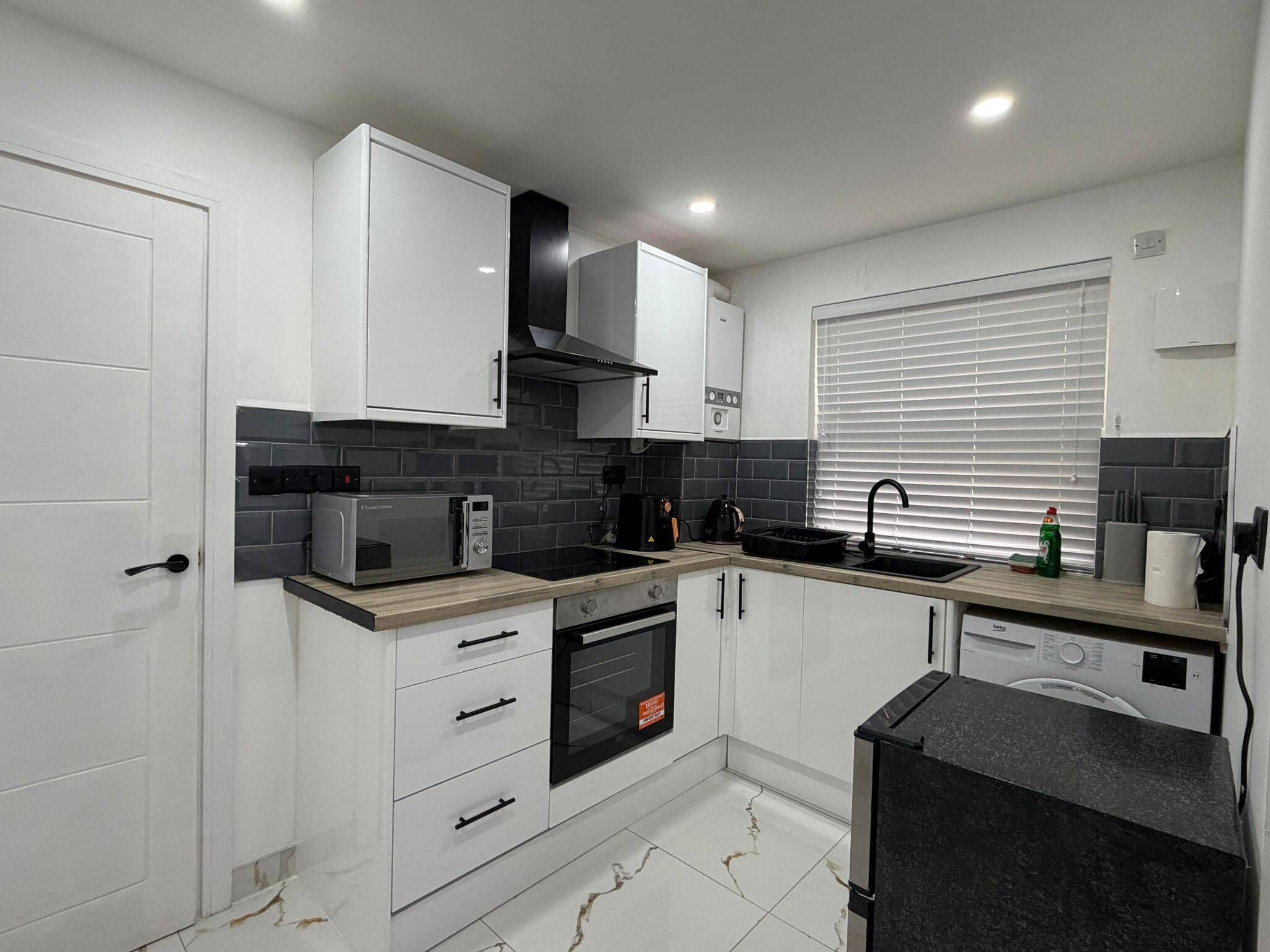 A modern kitchen with white cabinets, a black oven, a microwave, and a dishwasher.