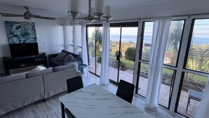 Ein modernes Wohnzimmer mit großem Fernseher, einer Couch und einem Esstisch.