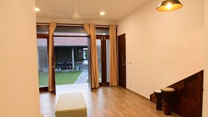 Una habitación con piso de madera, un banco, una puerta y dos tambores.