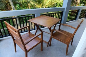 A wooden table and two chairs on a balcony with a black railing and a view of greenery. - DADY`S Place `63`- Sunset Villa - Ground floor - Beach in 2 min (Hikkaduwa)