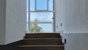 Una escalera que lleva a un balcón con vistas a palmeras y un cielo despejado.