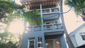 Un edificio de varios pisos con balcones, rodeado de palmeras.