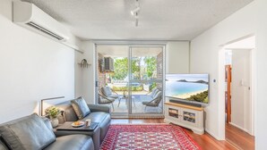 Uma sala de estar moderna com um sofá de couro, uma TV de tela plana e um tapete vermelho estampado.