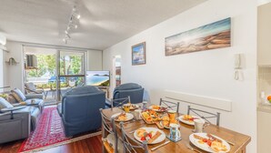Uma sala de estar moderna com área de jantar, janelas amplas e vista para o mar.