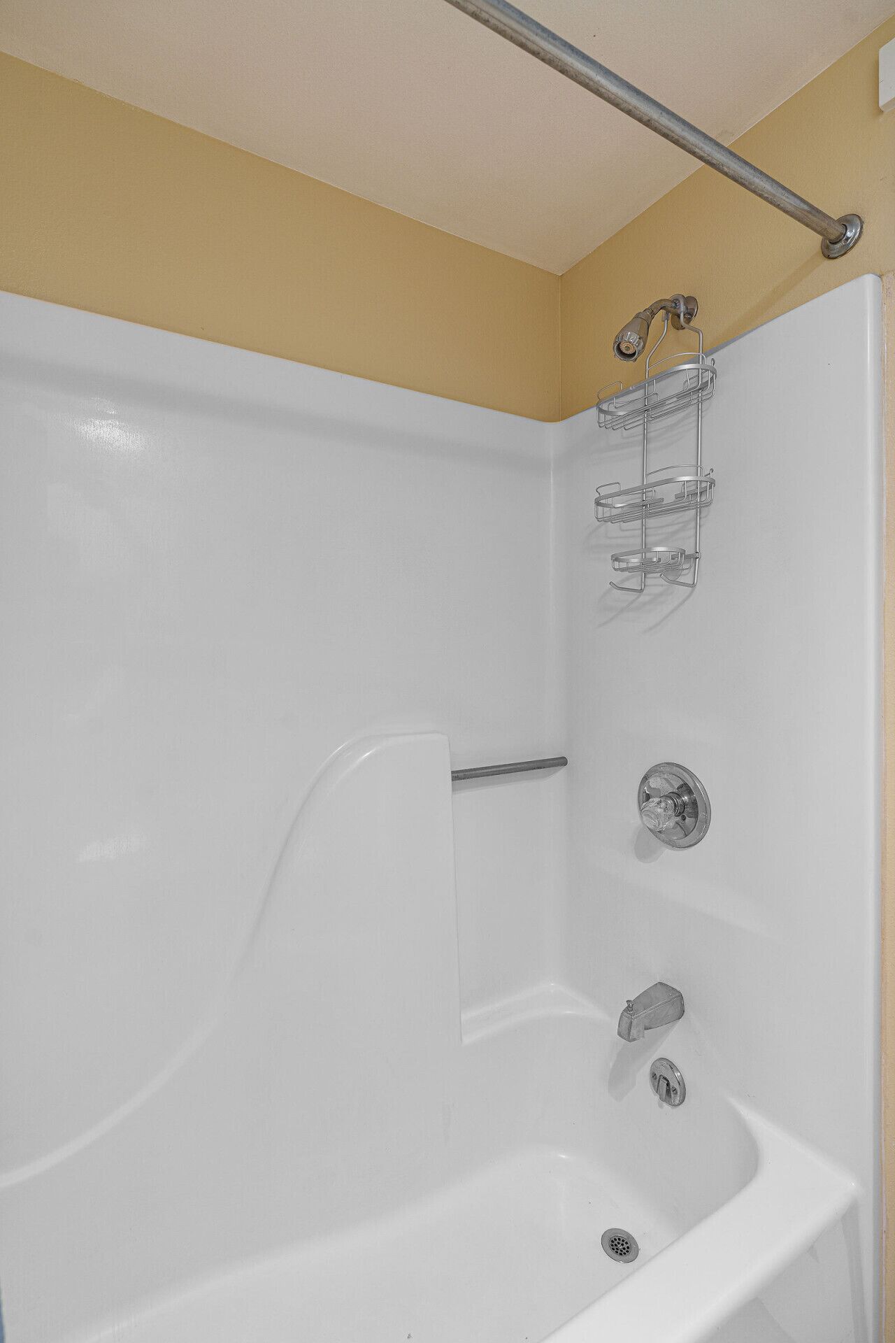 A white bathtub with a shower head, a metal towel rack, and a shower control panel.