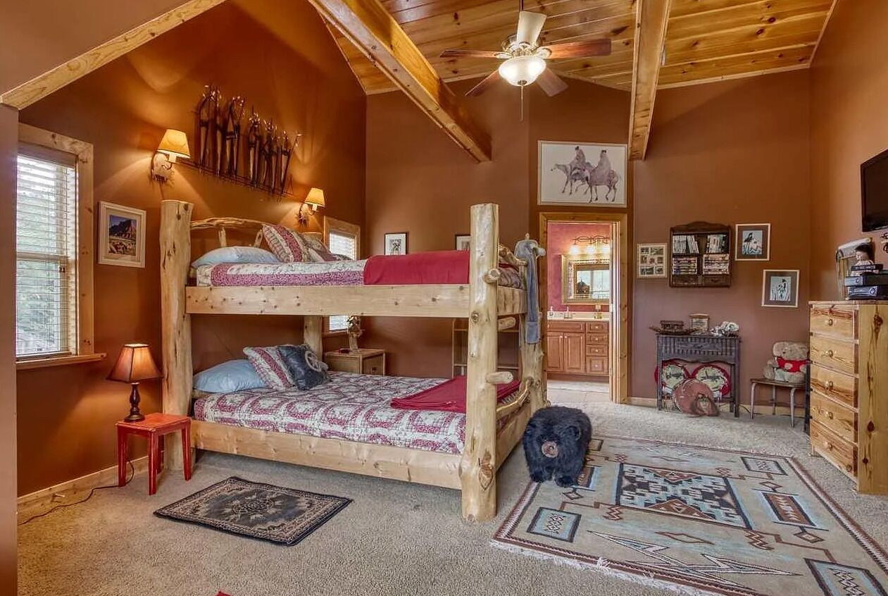 A cozy room with a bunk bed, a small table with a lamp, a rug, and a dog.
